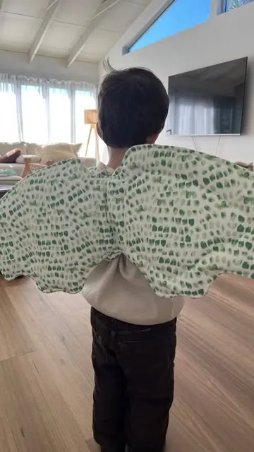 A child seen from behind wearing green spotted quilted wings